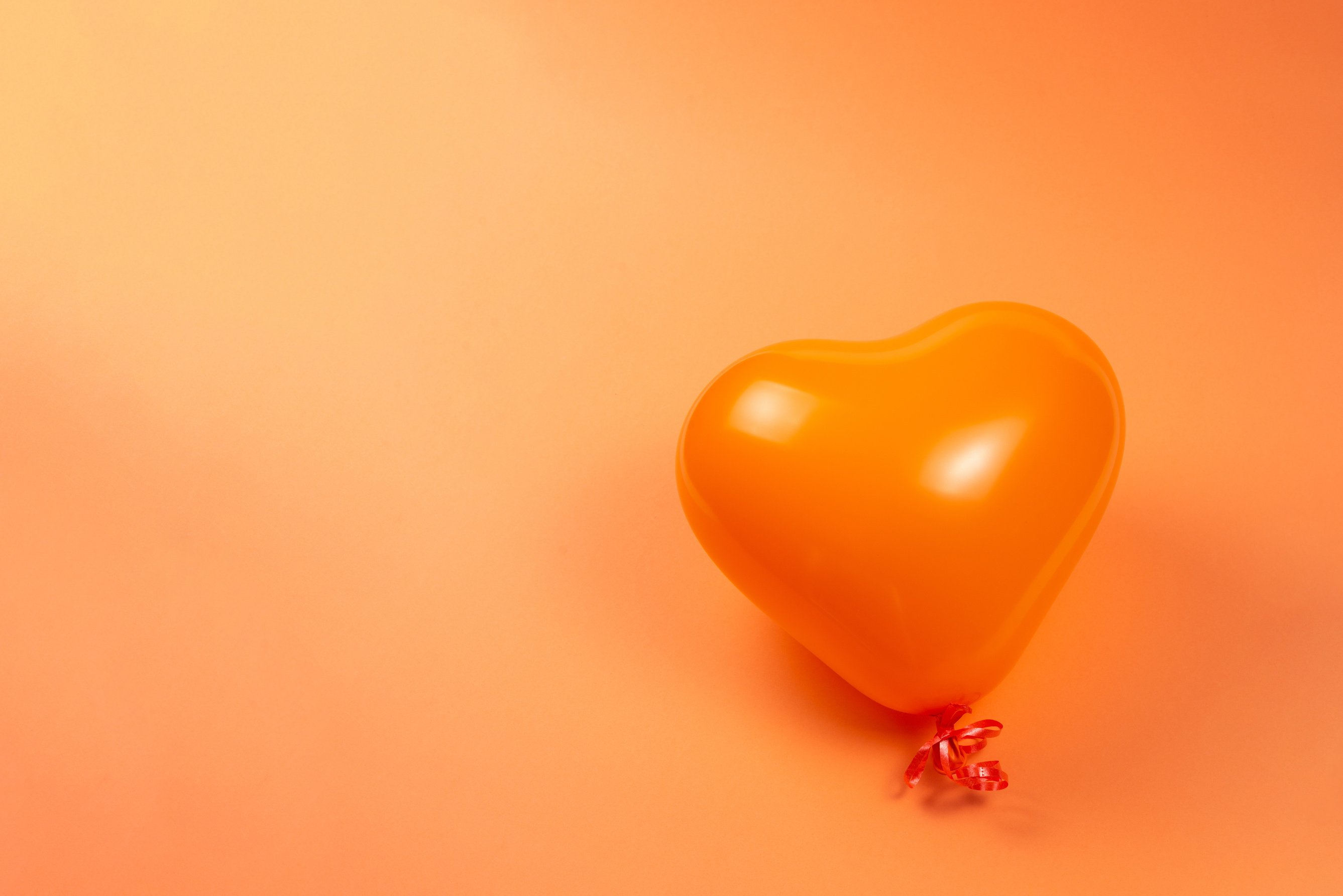 Orange heart ballon on orange background.