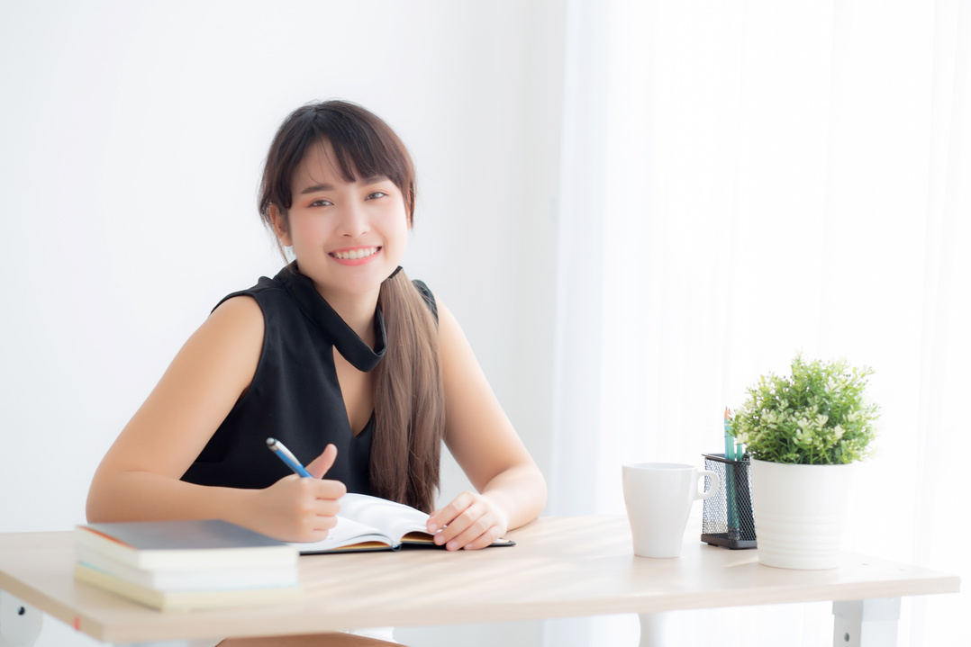 Woman Smiling While Studying at Home